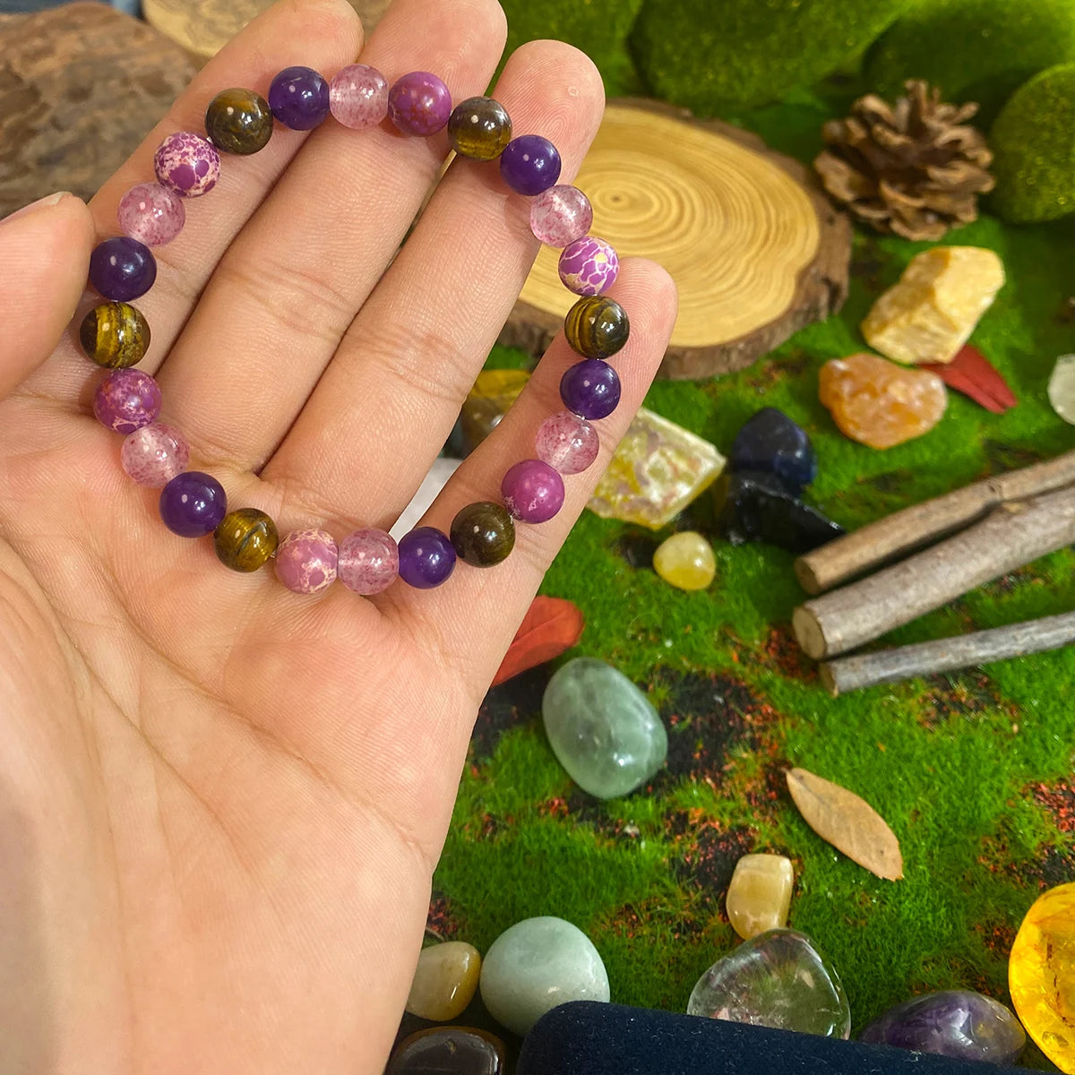 Hand holding a colorful beaded bracelet with a natural stone and crystal background