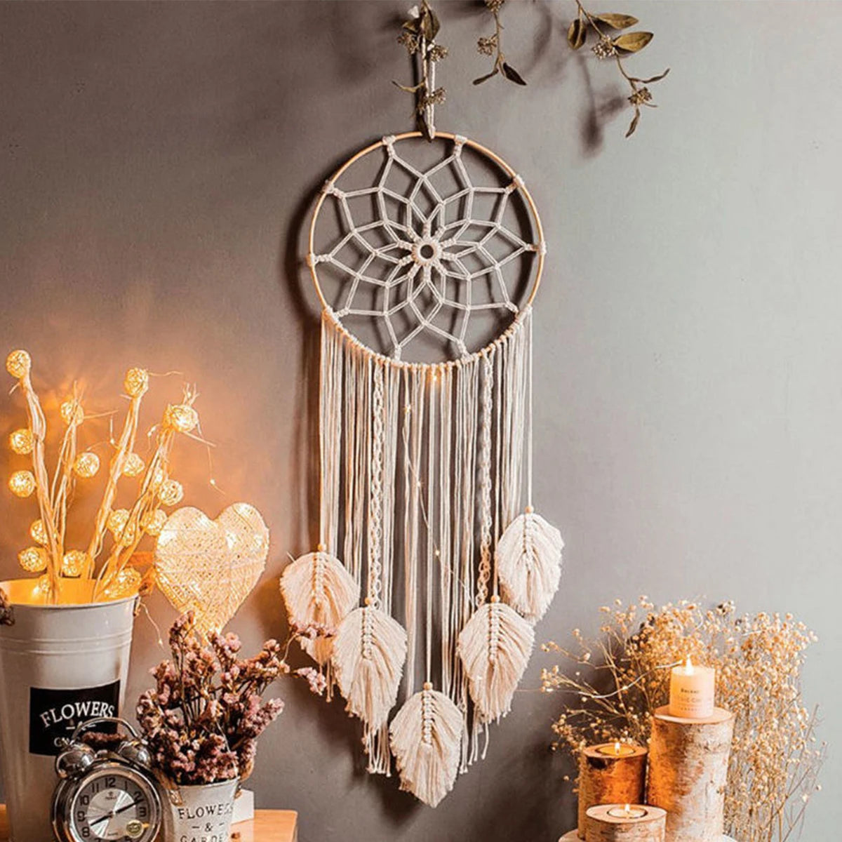 Decorative dreamcatcher hanging on a wall with candles and plants.
