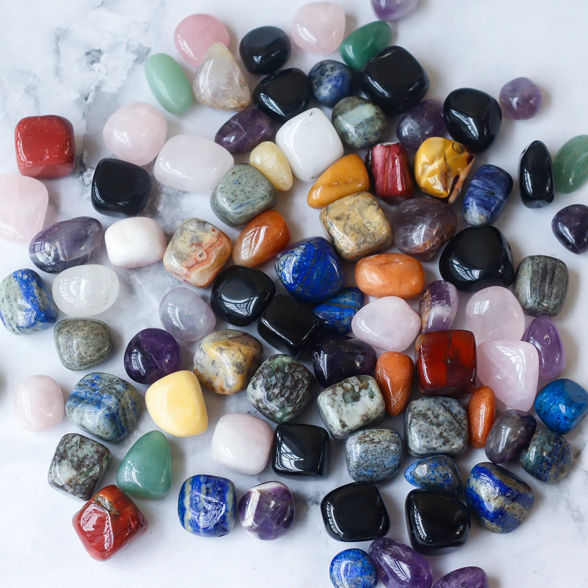 Assorted colorful gemstones on a white marble surface