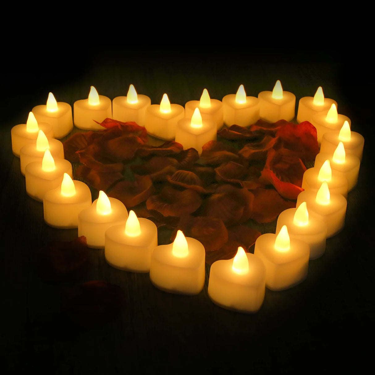 Heart-shaped arrangement of candles and rose petals on a dark background