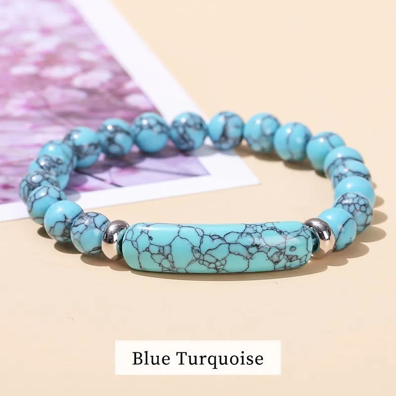 Blue turquoise beaded bracelet on a beige surface with a blurred pink and white background