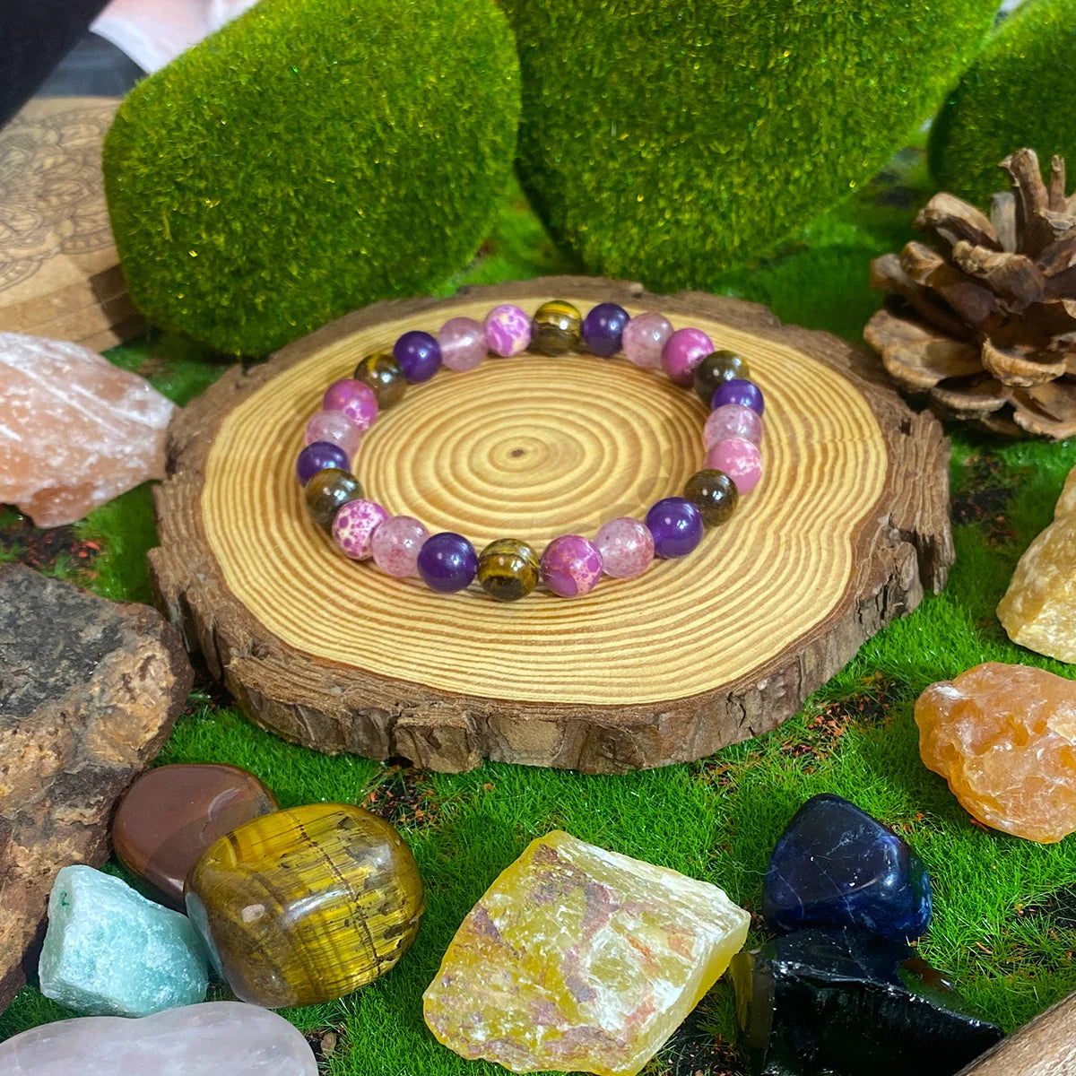 Multicolored beaded bracelet on a wooden stump with stones and moss in the background