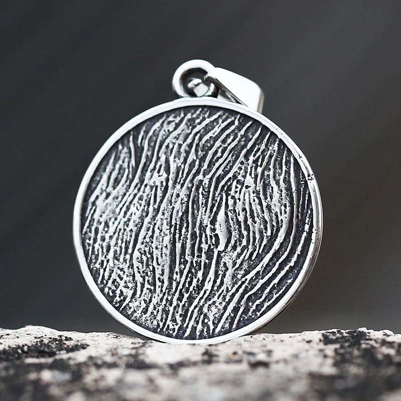 Silver pendant with textured design on a dark background