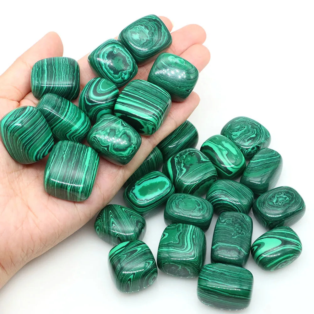 Hand holding green malachite stones against a white background
