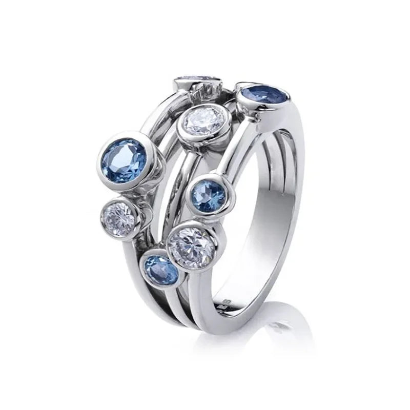 Silver ring with blue and clear gemstones on a white background