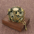 Decorative bronze pendant with chain on a wooden stand against a brown fabric background