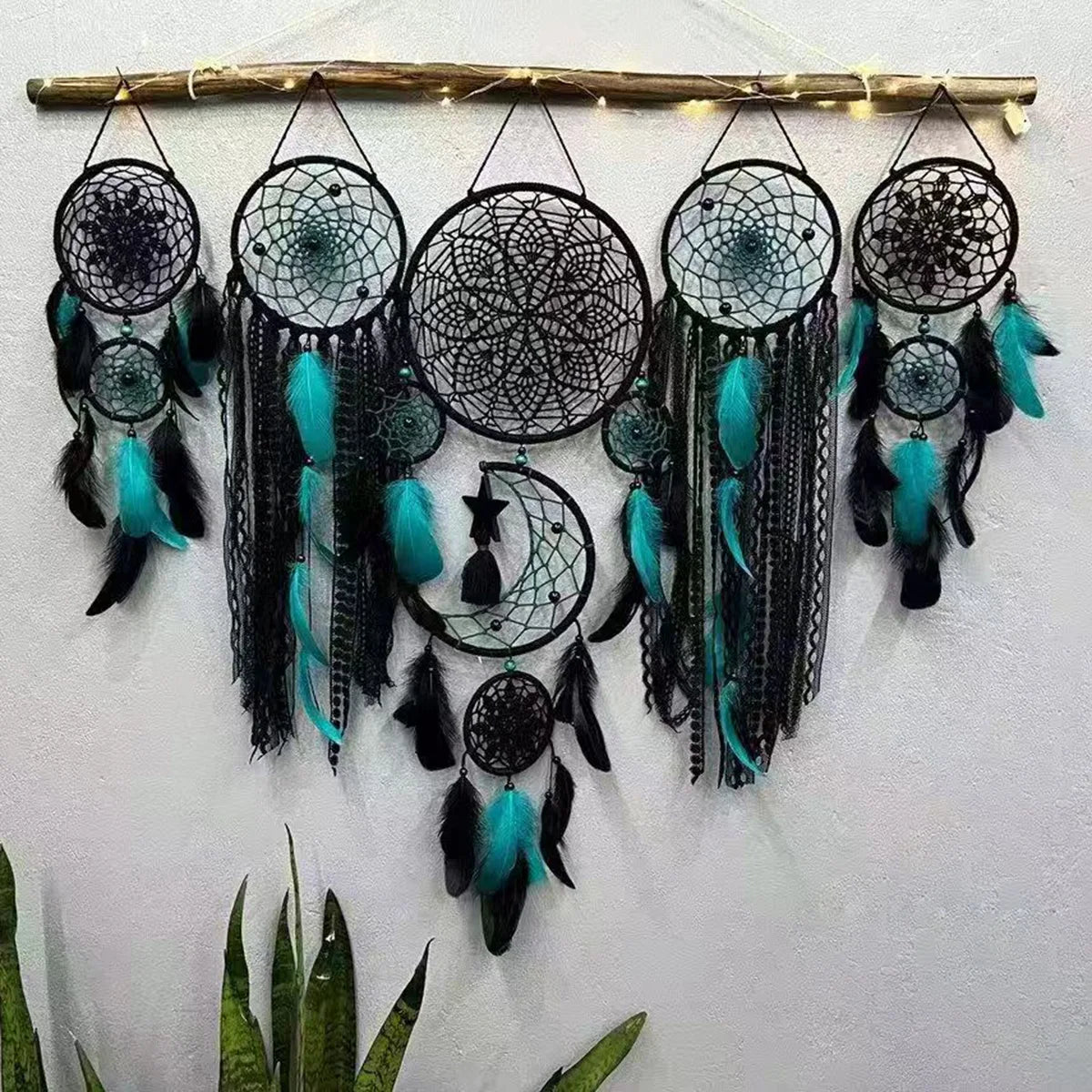 Set of dream catchers with teal and black feathers on a white wall.