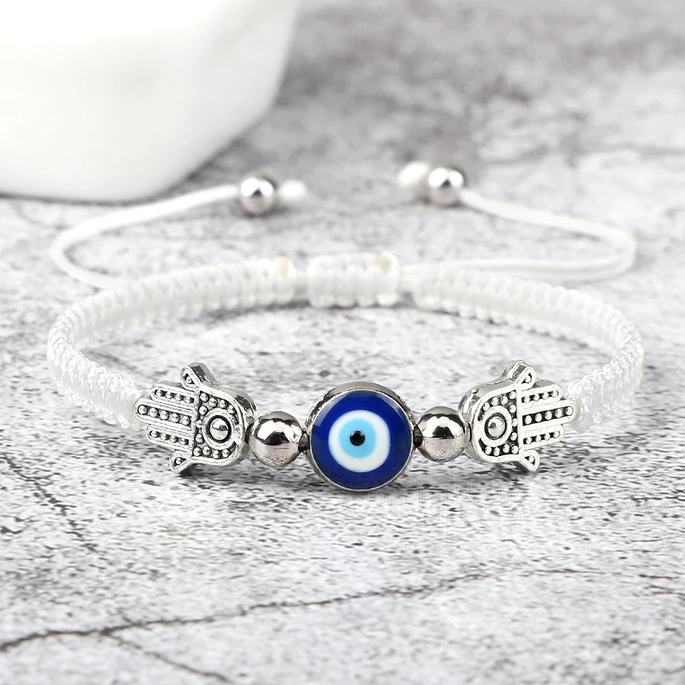 Bracelet with Hamsa hand and evil eye charm on a textured surface