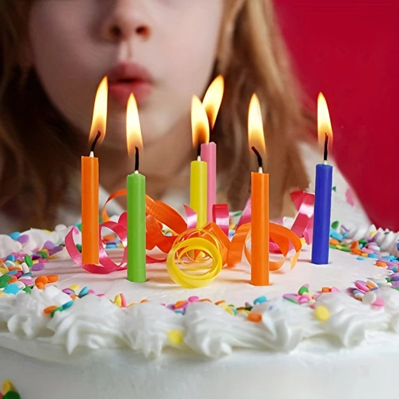 Child blowing out colorful candles on a birthday cake with a red background