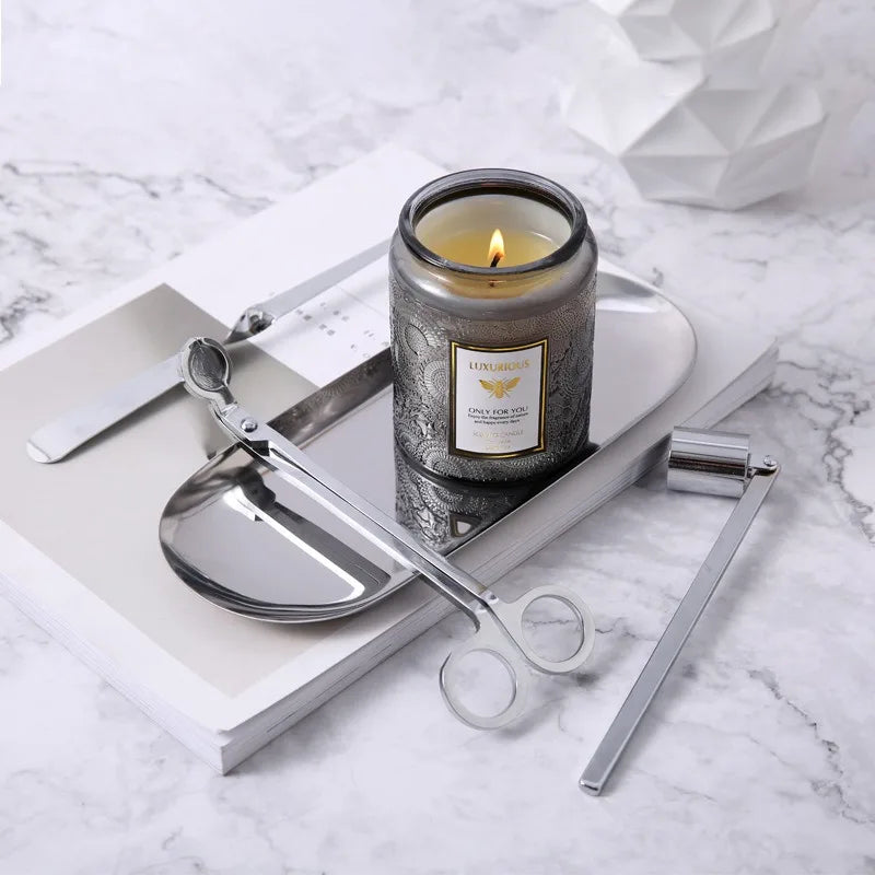 Candle in a decorative container with scissors on a marble surface