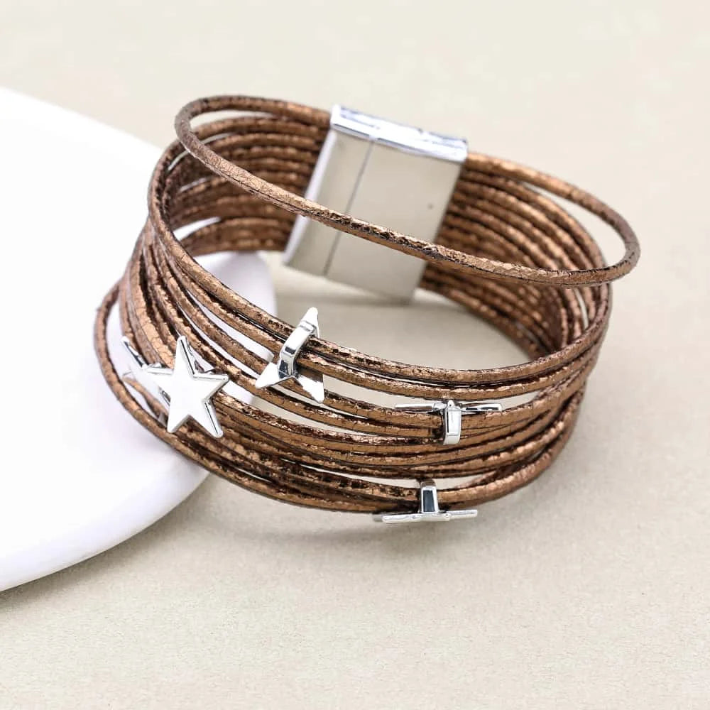 Brown leather bracelet with silver star and moon charms on a beige background