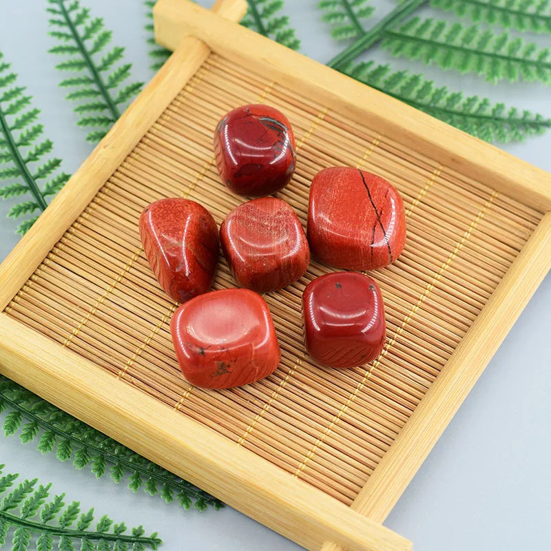 Red stones on a bamboo mat with green leaves in the background