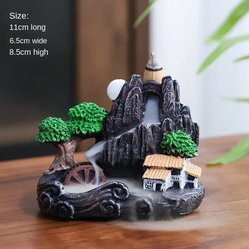 Decorative incense burner with mountain and village scene on a wooden surface