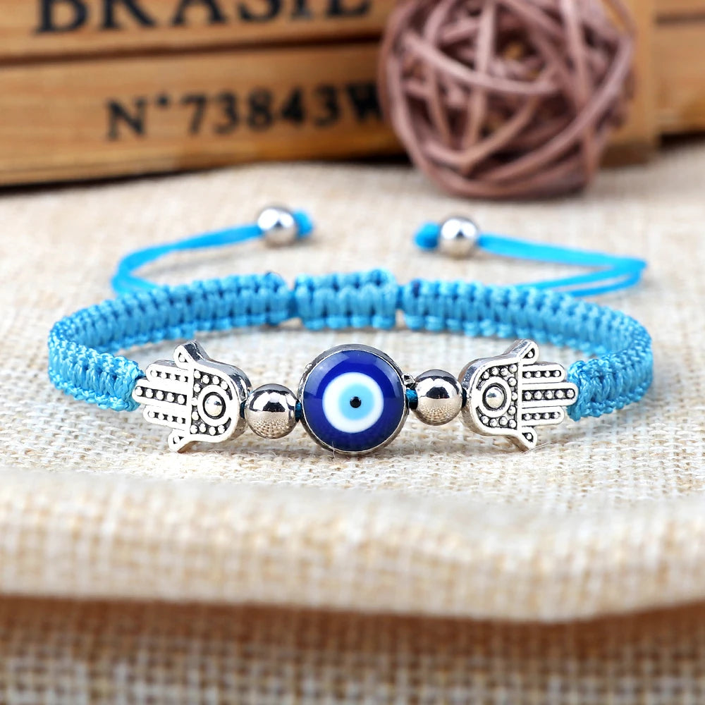 Blue bracelet with Hamsa hand and evil eye beads on a textured surface