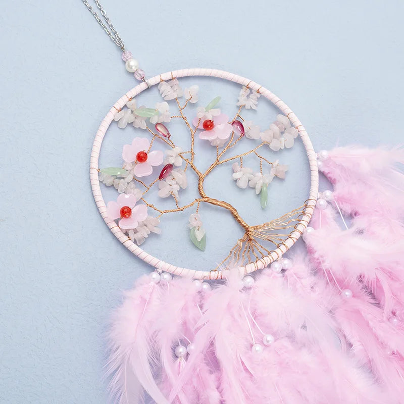 Decorative dreamcatcher with floral elements and pink feathers on a light blue background