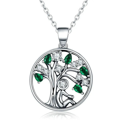 Silver tree-shaped pendant with green and clear stones on a white background, featuring the WOSTU brand.