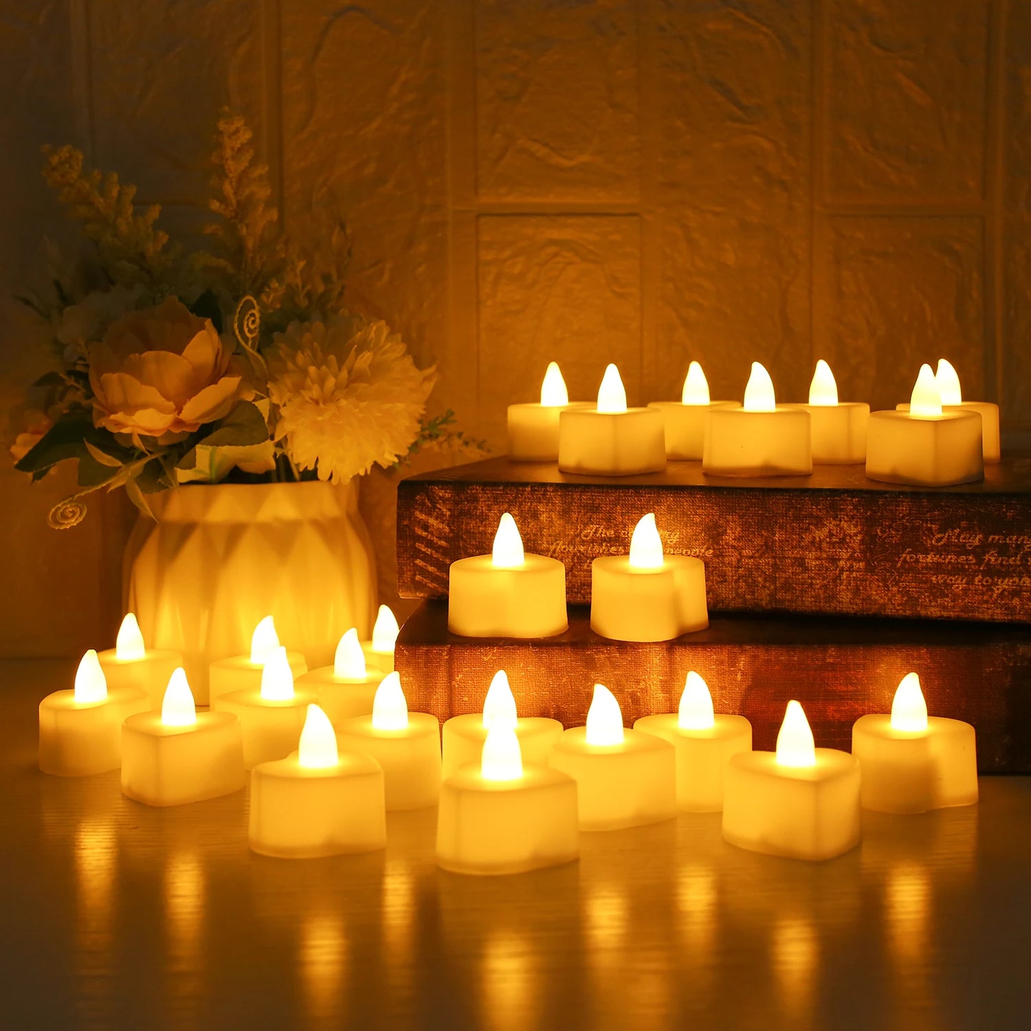 Flickering candles on a wooden surface with a vase of flowers in the background