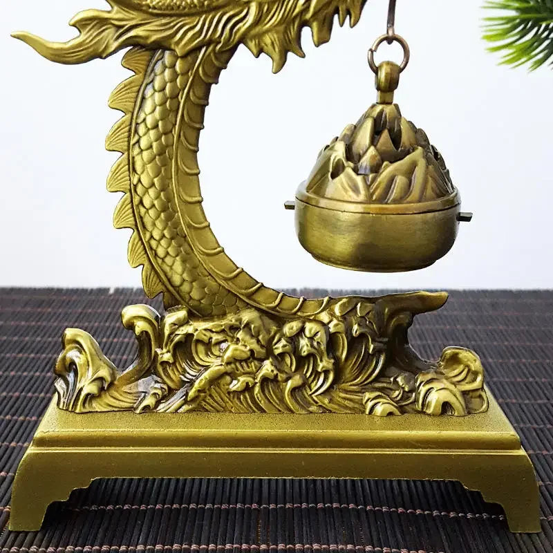 Decorative gold dragon incense burner on a textured surface