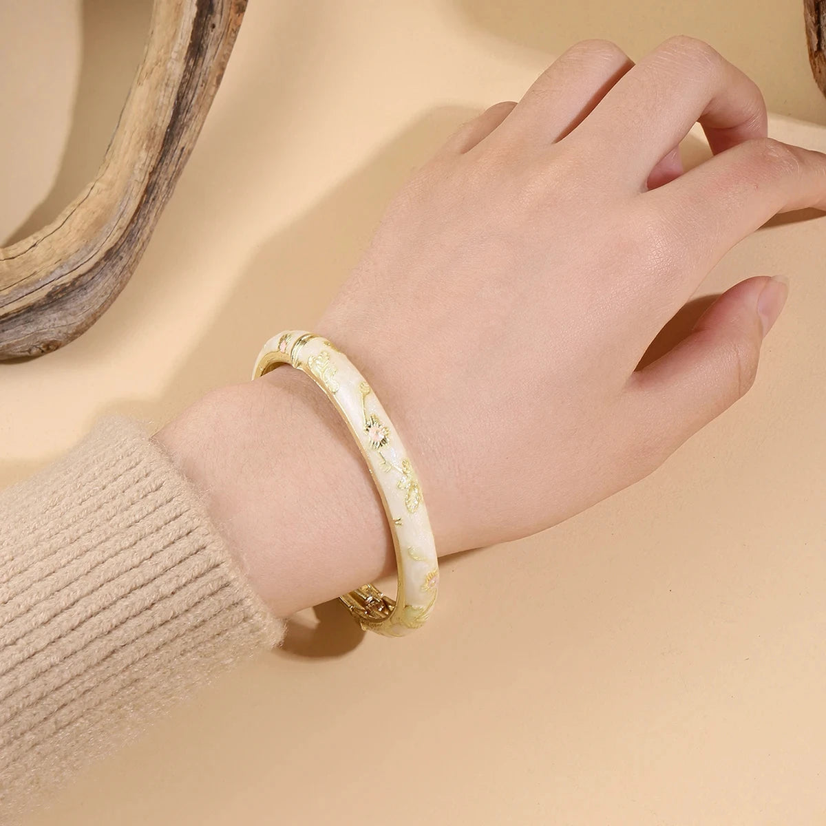 Gold bracelet on a wrist with a neutral background