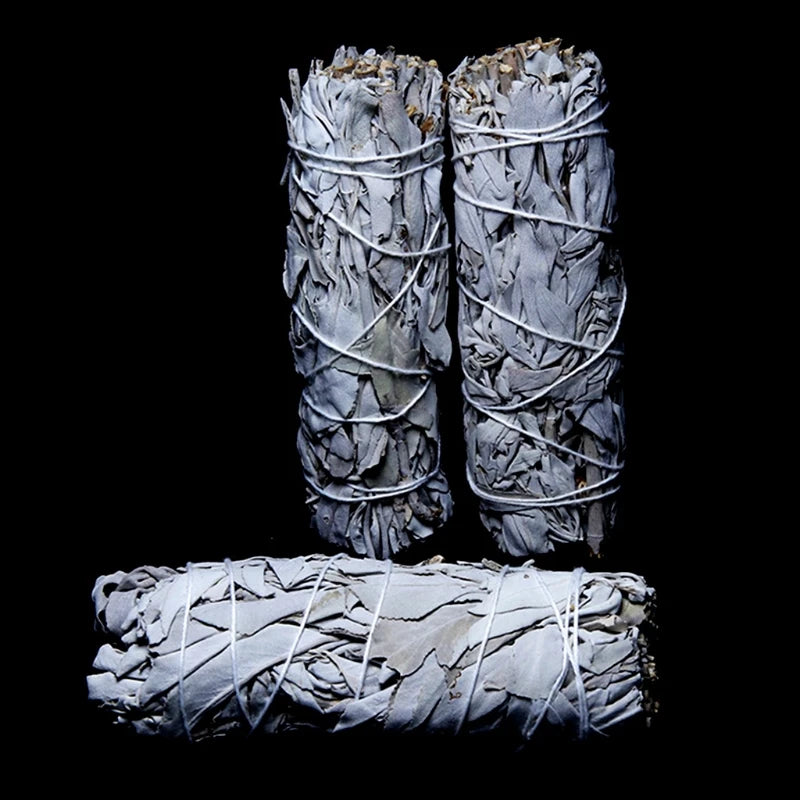 Three bundled sage smudge sticks on a black background