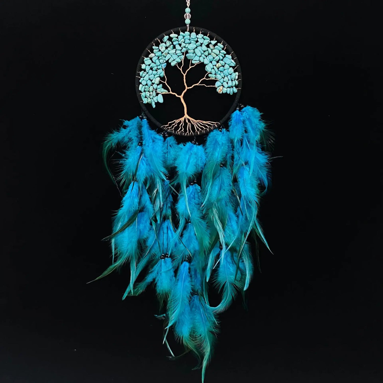 Turquoise dreamcatcher with feathers and tree of life design on a black background