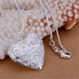 Silver heart-shaped locket with starfish design on a beige surface with coral background