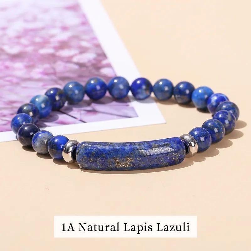 Blue lapis lazuli beaded bracelet on a beige surface with a blurred pink floral background