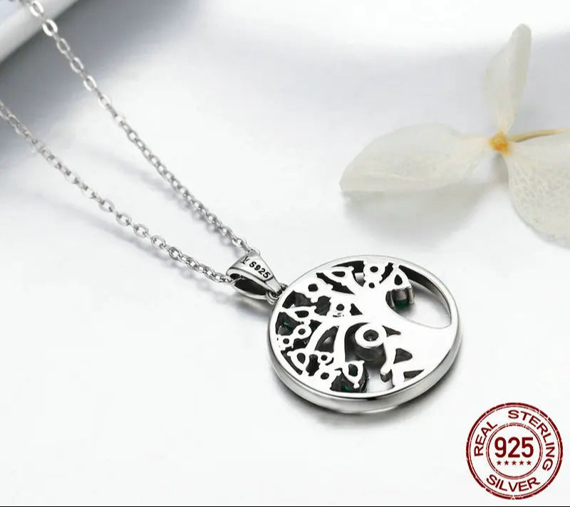 Silver necklace with a tree of life pendant on a white background, featuring the WOSTU brand.