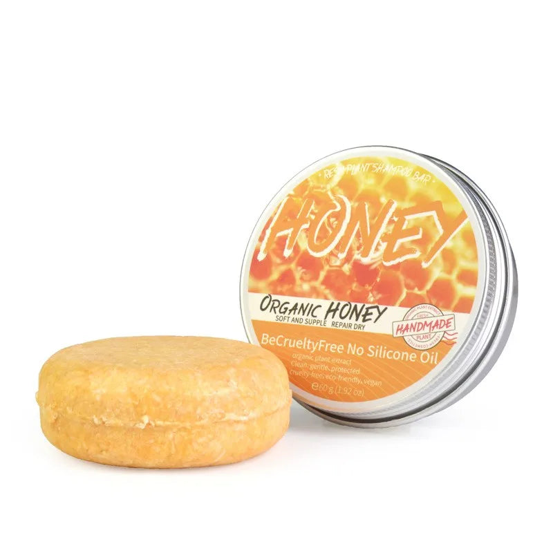 Bar of organic honey soap next to a tin labeled 'The Honey' on a white background