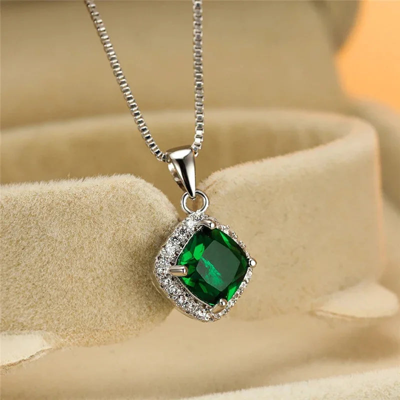 Silver necklace with a green gemstone pendant on a beige surface