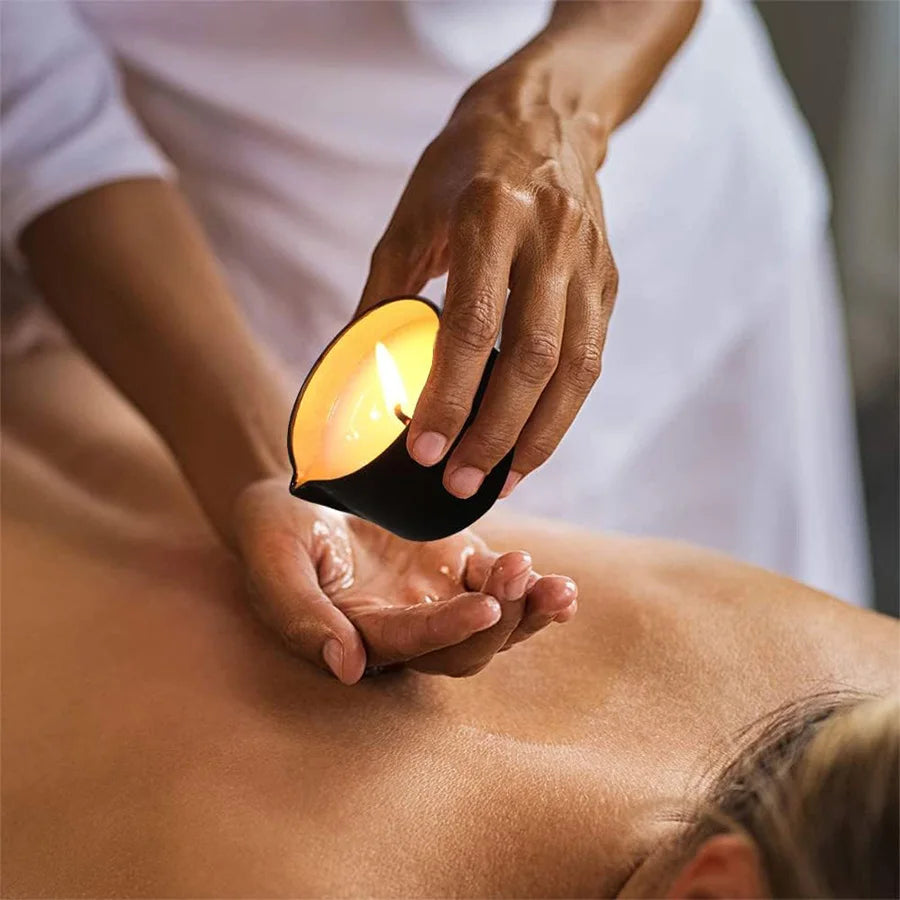 Hand holding a lit candle over another hand during a massage.