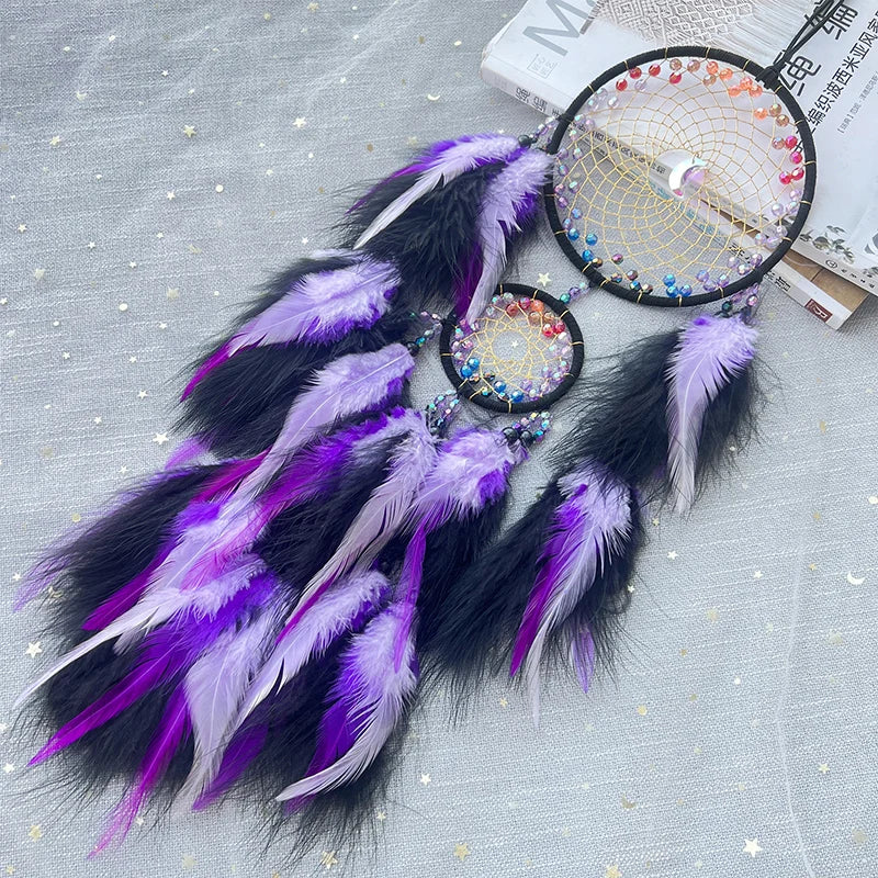 Dreamcatcher with purple and black feathers on a textured surface