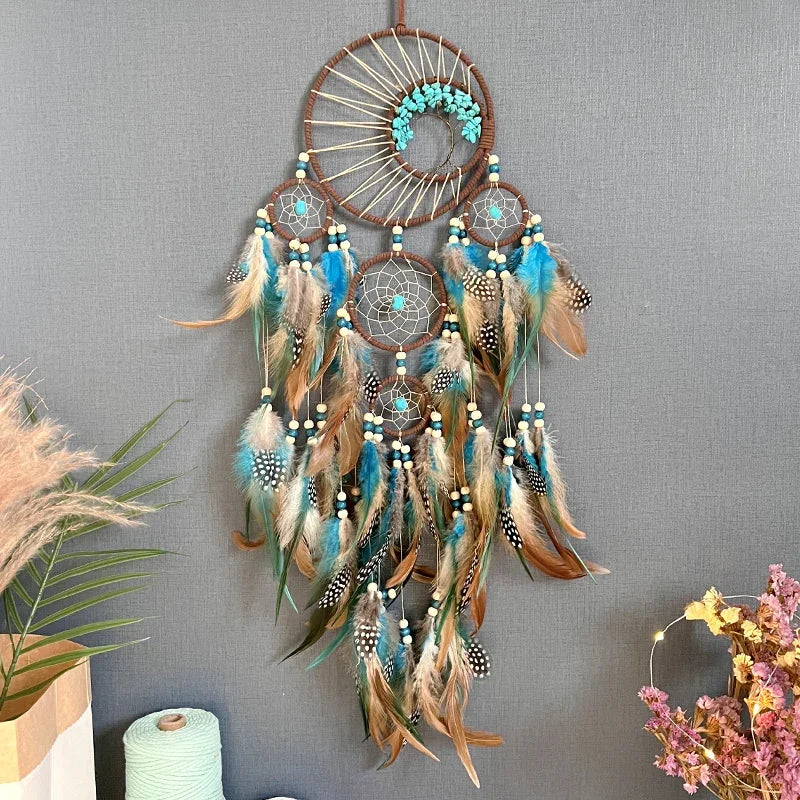 Decorative dreamcatcher with feathers hanging on a gray wall.