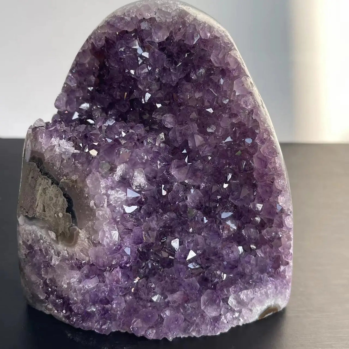 Amethyst crystal formation on a dark surface with a blurred background