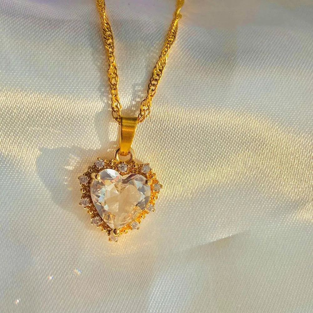 Gold necklace with a heart-shaped pendant on a white fabric background