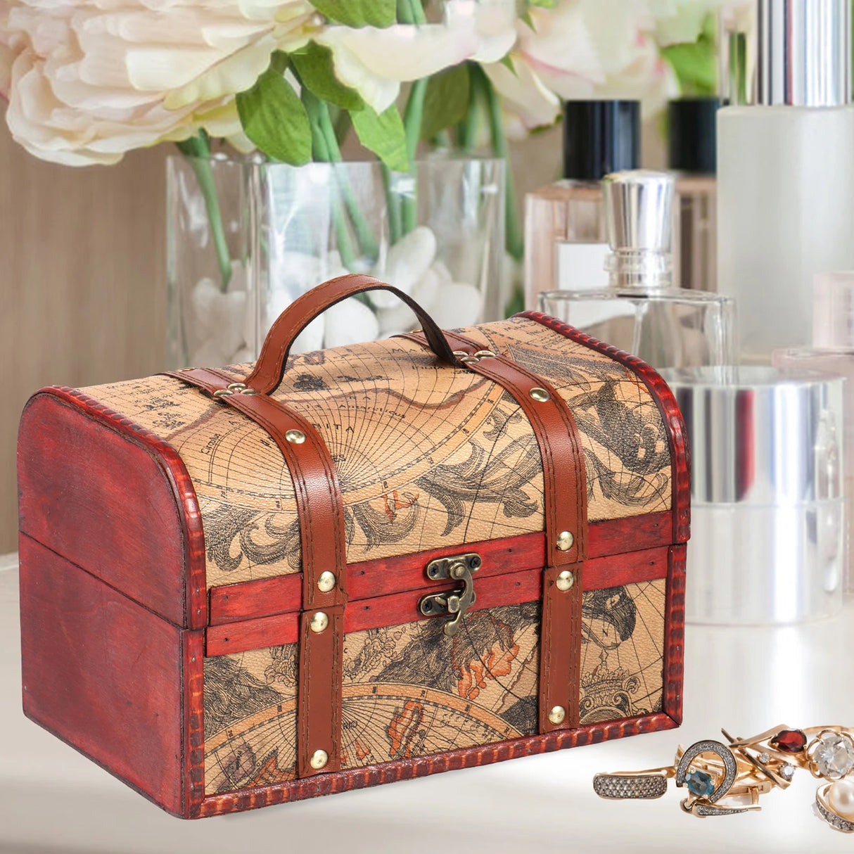 Decorative suitcase with world map design on a table with flowers and jewelry in the background