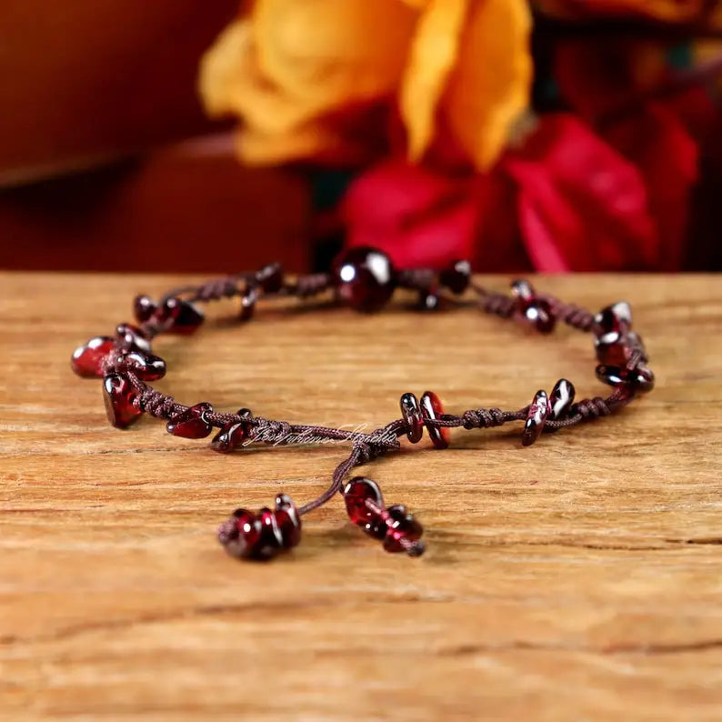 Garnet bracelet on a wooden surface with flowers in the background