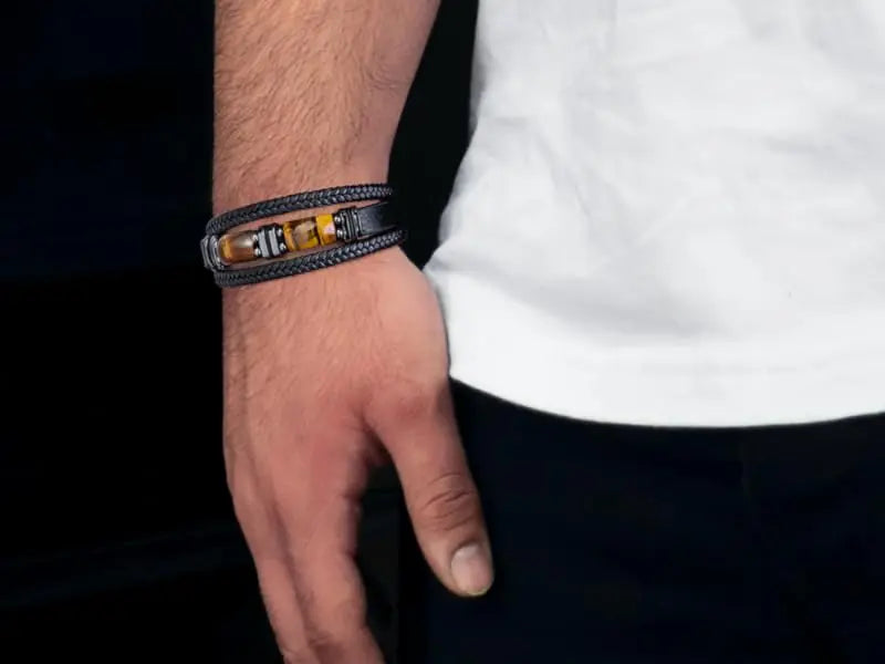 Close-up of a hand wearing a black leather bracelet with a white shirt background