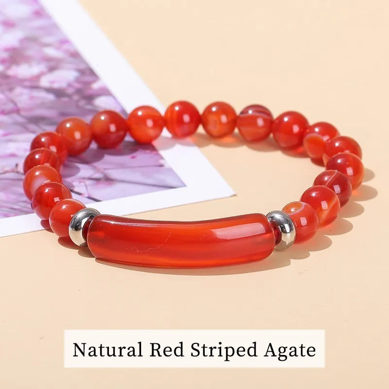 Red striped agate bracelet on a beige surface with a blurred background