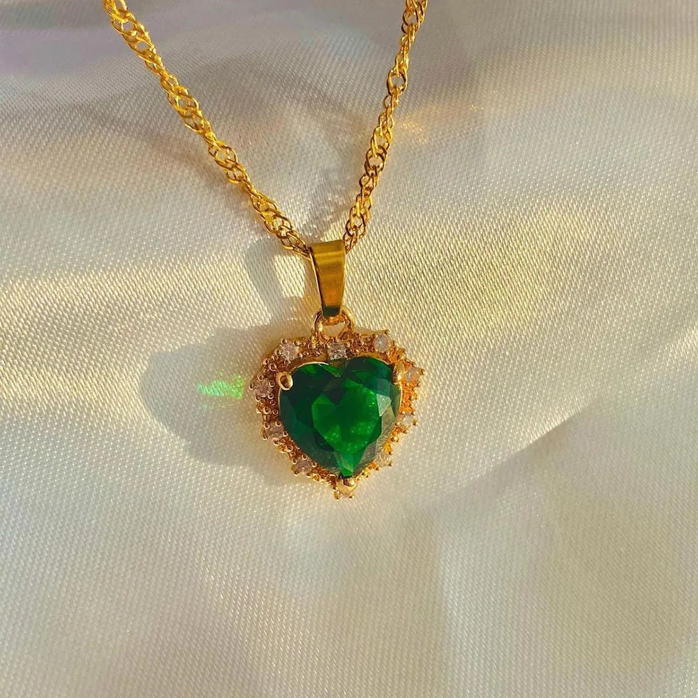Gold necklace with a green heart-shaped pendant on a light background