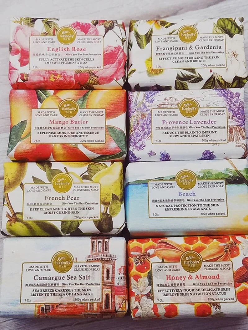 Assorted soap bars with decorative packaging and labels on a wooden surface.