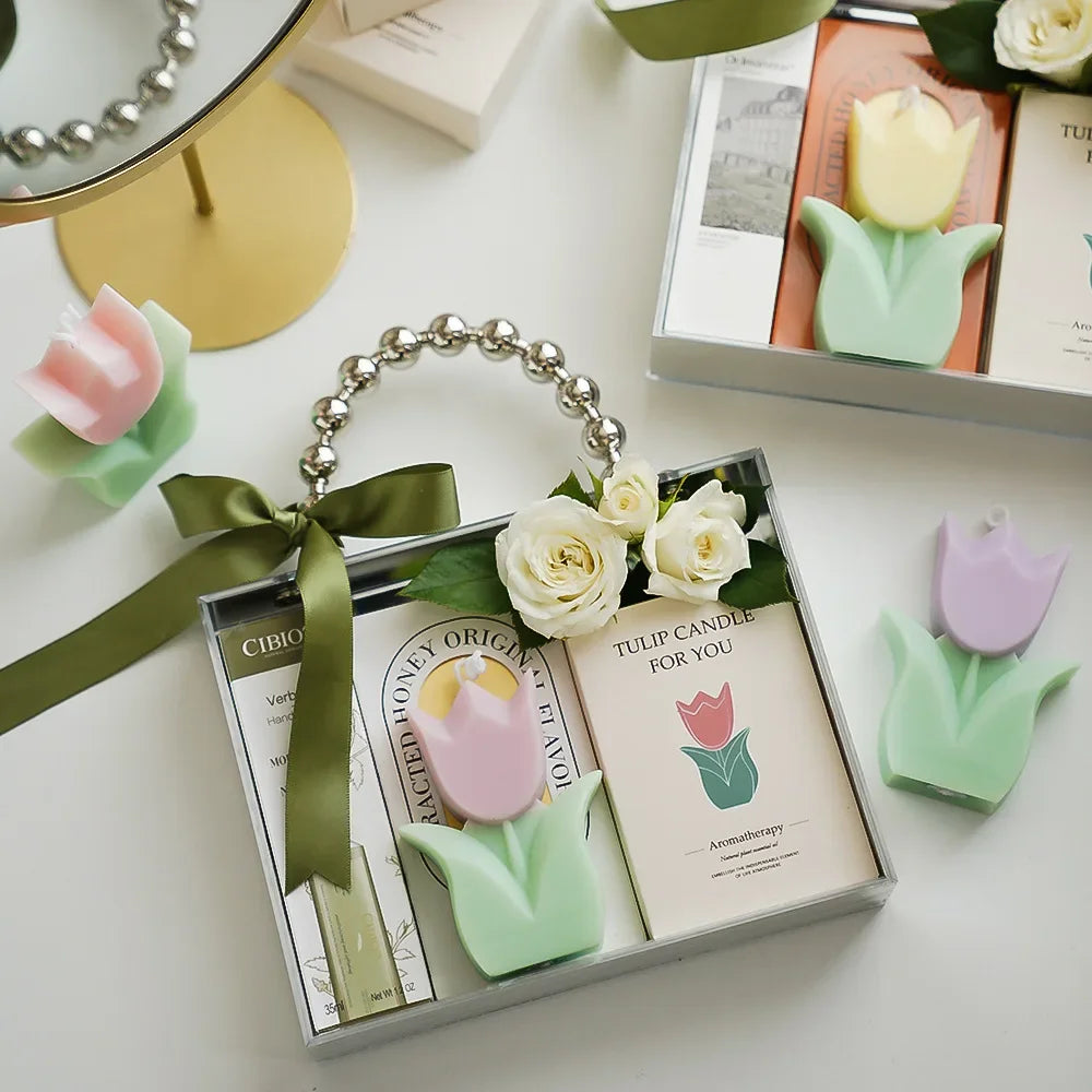 Tulip-shaped candles in a box with decorative ribbons on a white surface