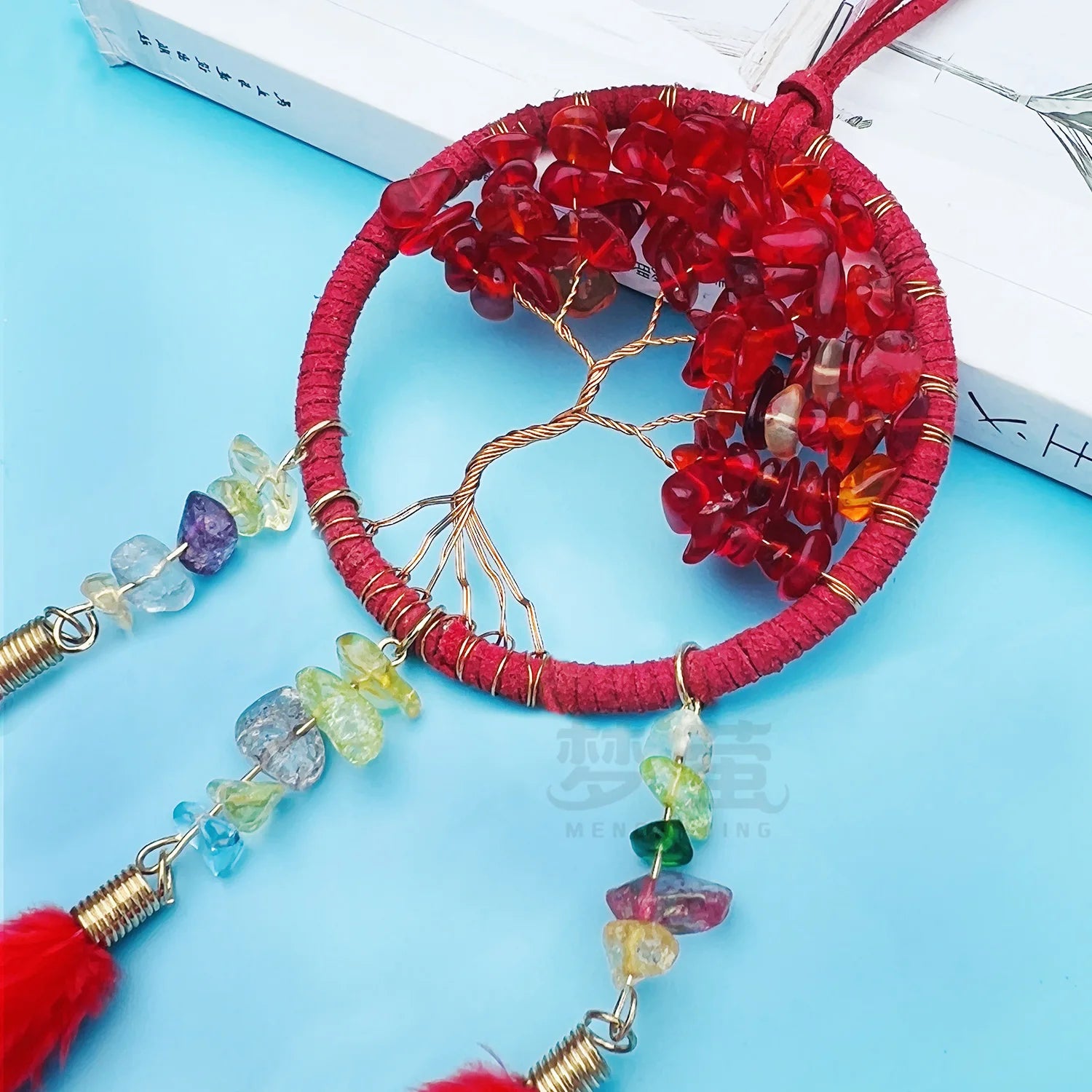 Decorative red beaded item with colorful tassels on a blue background