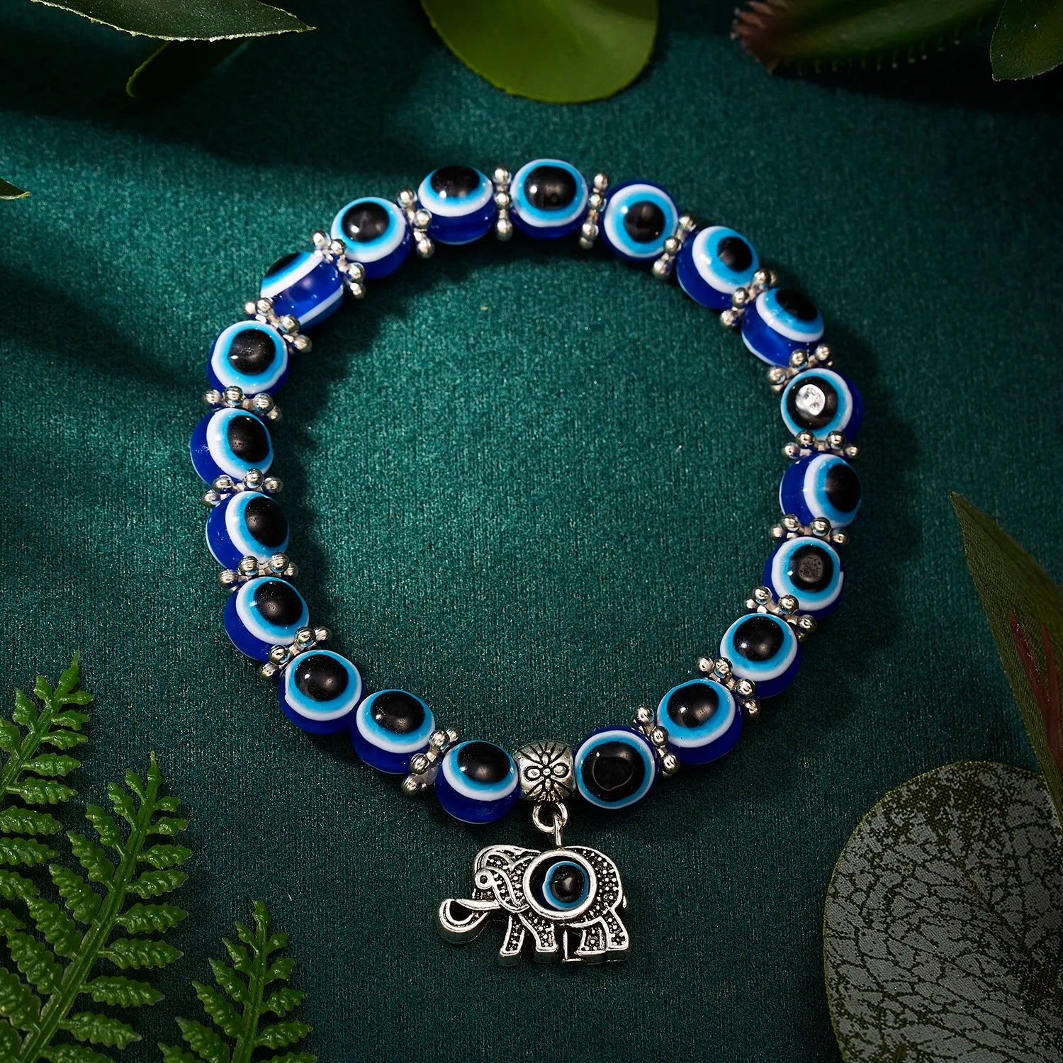 Bracelet with blue and black beads and an elephant charm on a green background