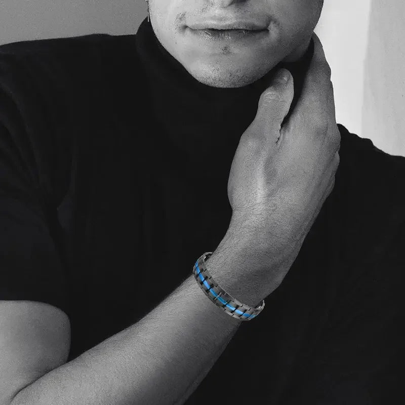 Person wearing a bracelet with blue accents, holding their neck.