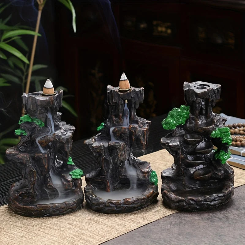 Three decorative incense burners shaped like miniature waterfalls on a table.