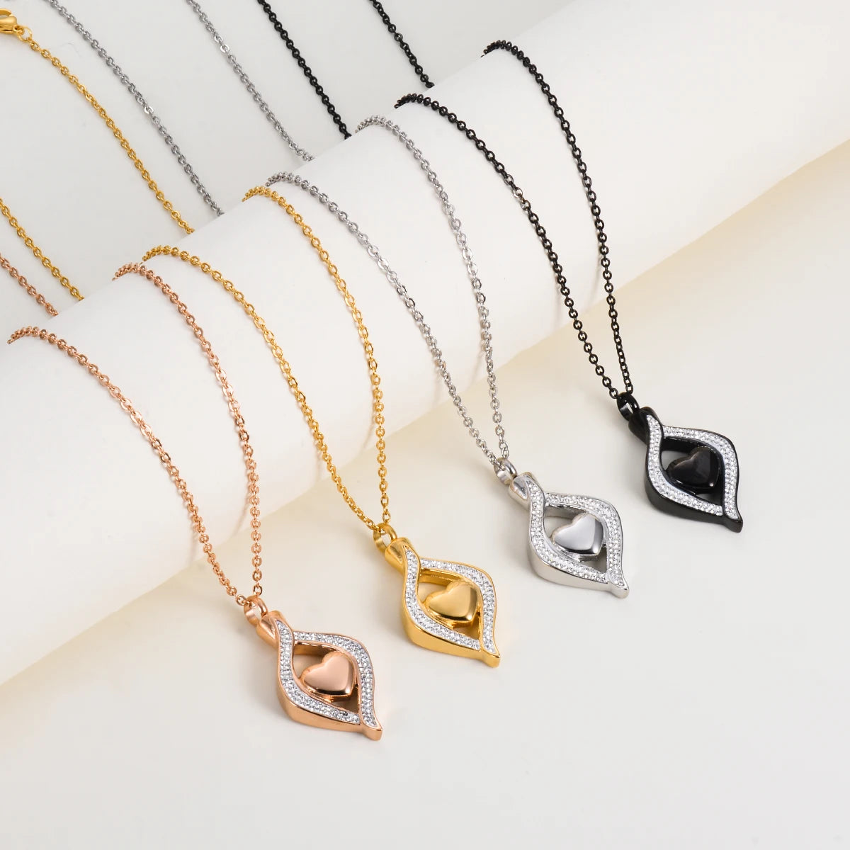 Four necklaces in gold, rose gold, silver, and black on a light background