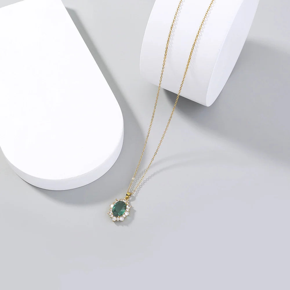 Gold necklace with a green gemstone pendant on a white surface