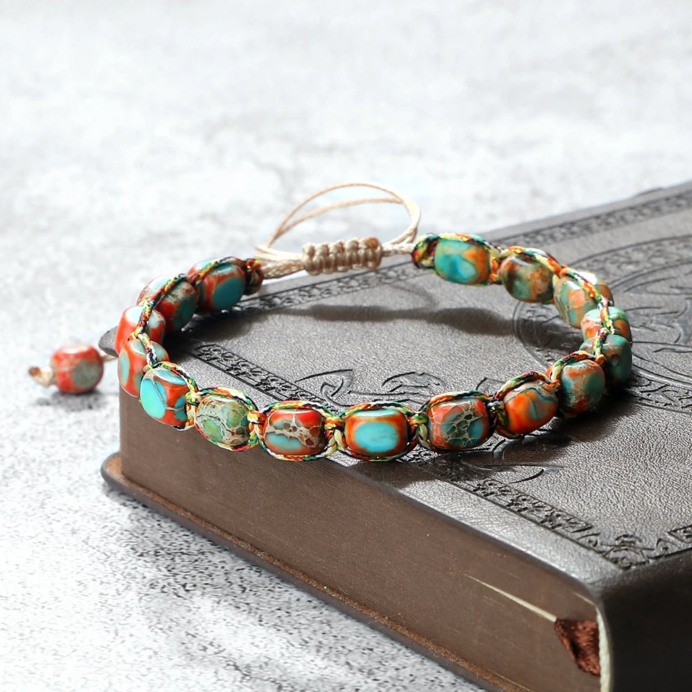 Beaded bracelet with turquoise and orange stones on a textured surface