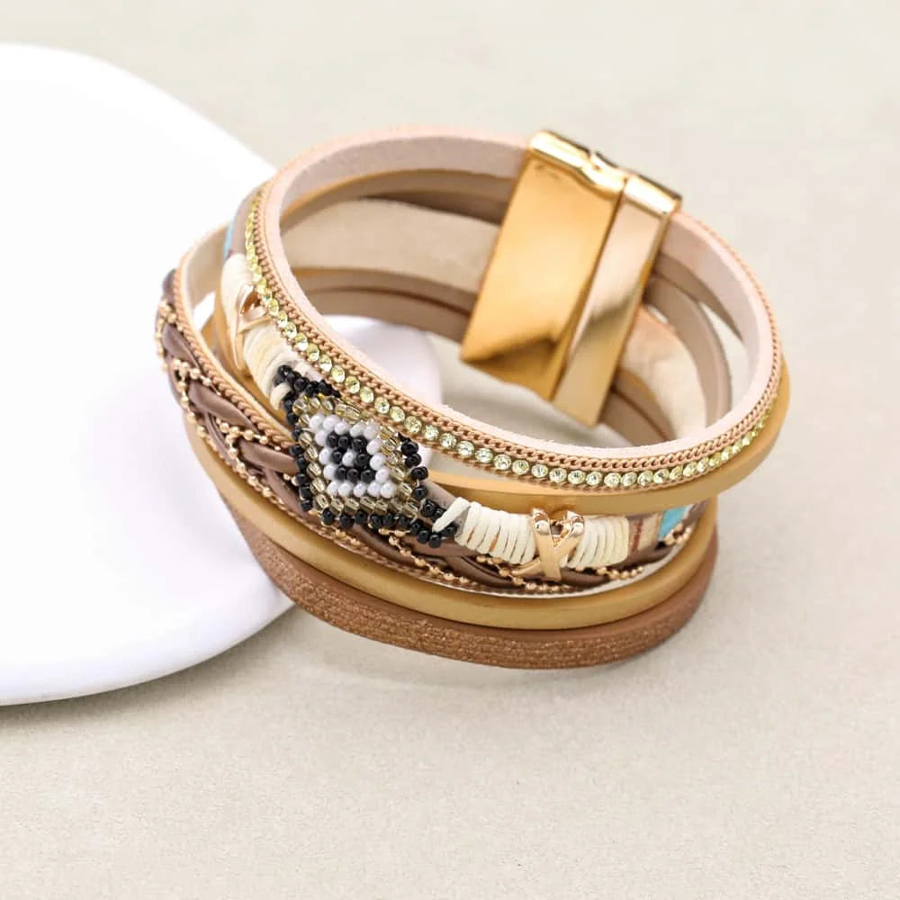 Stack of decorative bracelets with gold clasp on a light background